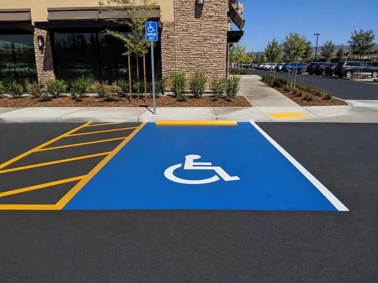Blue ADA accessible parking stall with wheelchair symbol and yellow hatched access aisle