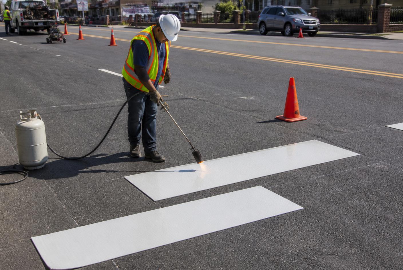 ARIMA crew member heat-applying a preformed thermoplastic crosswalk bar with a propane torch